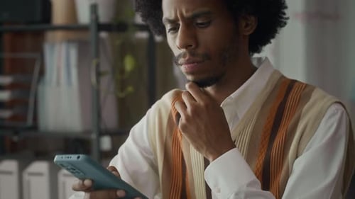 Thoughtful Businessman Texting Message to Partner on Smartphone at Office Desk