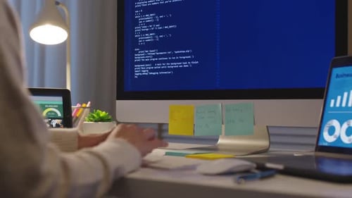 Mujer programadora trabajando en la oficina detrás de dos pantallas