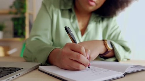 Closeup View of Young Businesswoman Writing on Notebook at Office