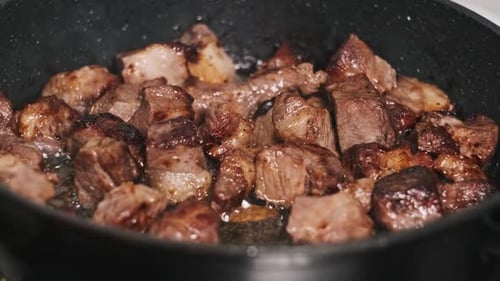 Juicy Pieces of Pork Meat are Cooked in a Frying Pan in a Home Kitchen