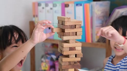 Cute Asian siblings having fun playing Jenga together.