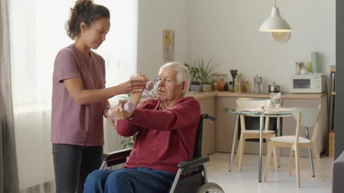 Young Woman Helping Senior Man Exercise with Dumbbells
