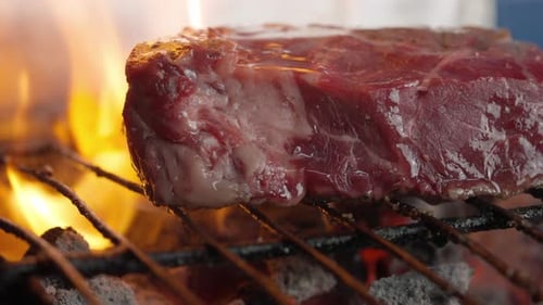Close-up of grilled fillet steak between flames and embers of barbecue charcoal