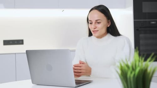 Woman Talking on Laptop in Bright Modern Kitchen