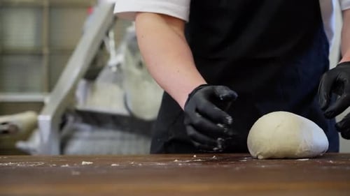 Kneading Dough and Shaping Loaves of Bread From It By a Professional Baker
