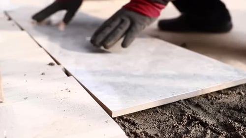 Real shot of decoration workers laying floor tiles, Installing a large ceramic tile