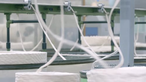 Cotton being spun into yarns. Textile factory production processes.