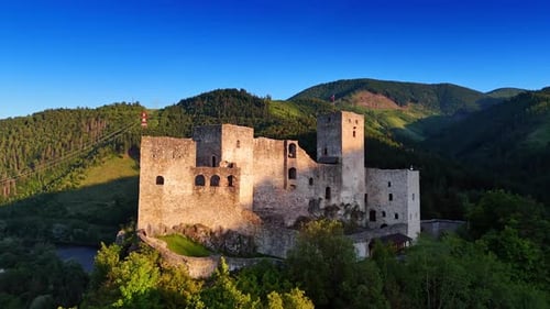 Historic castle ruins in a green valley. Ancient castle ruins rise amid lush hills under a blue sky
