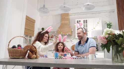 Charming Young Family Celebrating Easter with Traditional Colorful Eggs