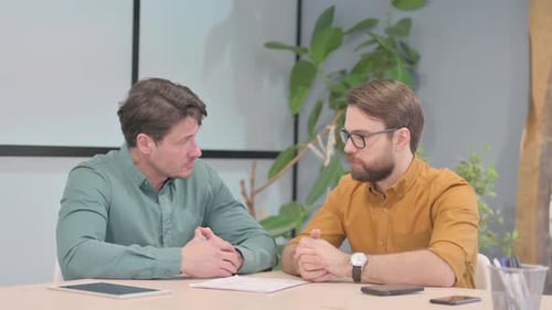 Two Businessmen Talking at Office Desk