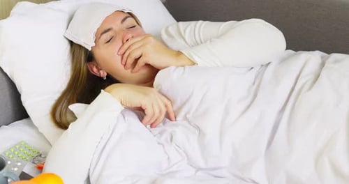 Young Woman Lying in Bed, Coughing