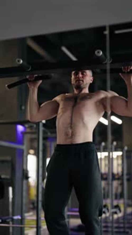 Muskulöser Athlet macht Klimmzüge im Fitnessstudio