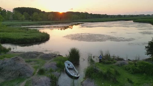 Person Fishing by River at Sunset