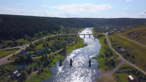 Aerial View of a Long Bridge Above the Wide River in Sunset