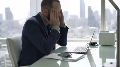 Young businessman suffering from headache while working overtime in modern office