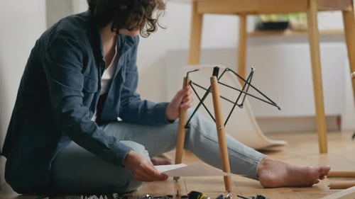 Une personne assemblant des meubles avec des instructions dans un cadre intérieur confortable par un après-midi calme