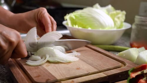 Slicing Fresh White Onions On Wooden Board With Chinese Cabbage Leaves In A Bowl In Background. clos