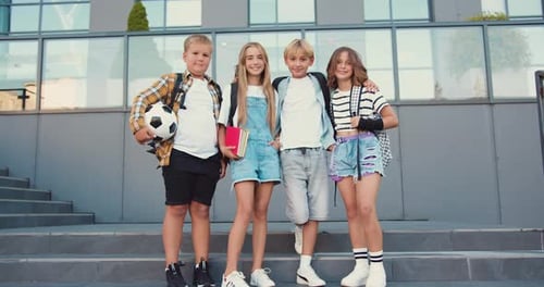 Portrait of smiling cheerful school children that hugging each other and smiling in camera, outdoors