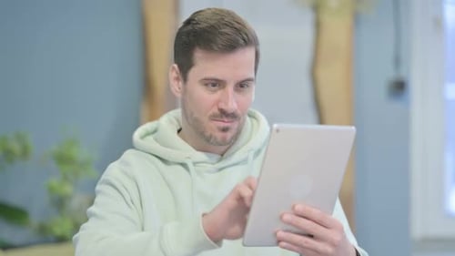 Young Adult Excitedly Using Tablet Indoors
