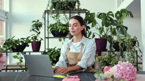 Woman Uses Laptop in Plant-Filled Flower Shop