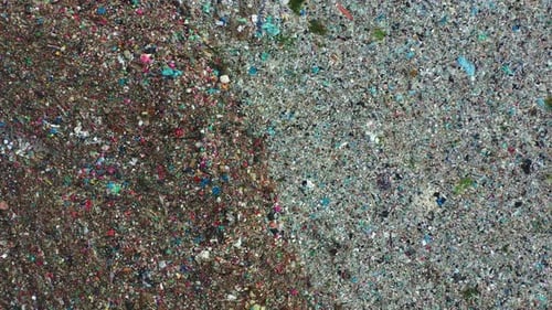 Aerial top down view, flyover a sprawling landfill with vast, unsorted waste piles starkly illustrat