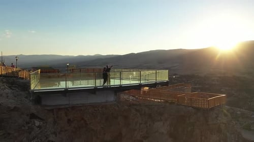Aerial View Of Couple Watching The View From The Glass Terrace At Sunset