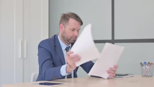 Professional Man Reviews Documents in Office Setting