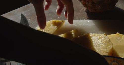 hands slicing pineapple into pieces, close up, slow motion