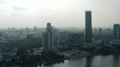 Top view of modern gray city in cloudy weather. Stock footage. Grey cloudy city with river and fog