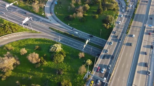 Drone shot starting low and panning up and to the right over a highway and revealing a big city