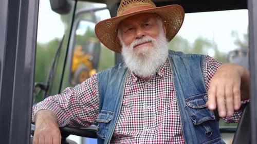 Senior Man Smiling Inside Tractor on Farm