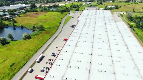 Aerial Shot of Truck with Attached Semi Trailer Leaving Industrial Warehouse/ Storage Building/ Load