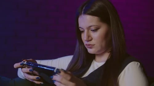 Woman Playing Handheld Game Console at Night