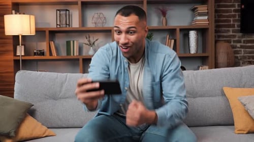 Excited Dark Skinned Guy Cheers for Favorite Football Team in Mobile Phone