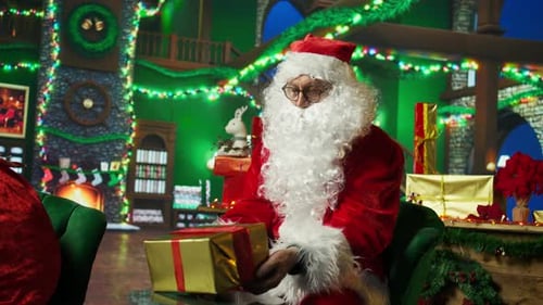 Santa Claus wraps a present in festive room