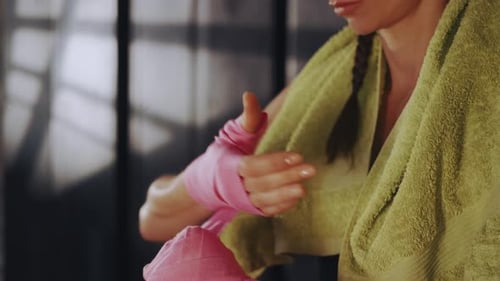 Frau wickelt Hände mit Boxbandagen im Fitnessstudio