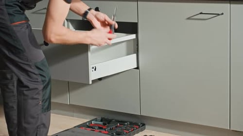 Carpenter Installing and Adjusting Drawer Front in Modern Kitchen Cabinet