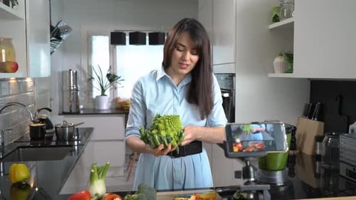 Woman Recording Video in Kitchen Holding Broccoli