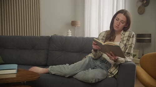 Woman Reading Book, Relaxing on Sofa at Home