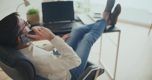 Adult Speaking on Cell Phone with Feet on Desk
