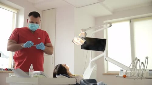 A Dentist is Examining a Patient 's Teeth in a Dental Office