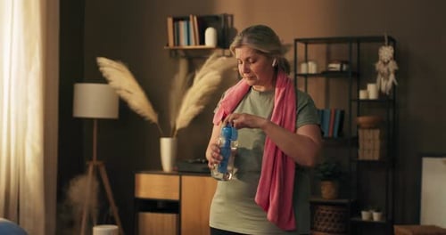 Woman Wipes Sweat and Drinks Water after Exercising