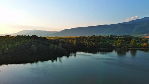 Lake with Clear Water and Stone Shore in Spruce Forest with Fir Trees Against a Daytime Sky