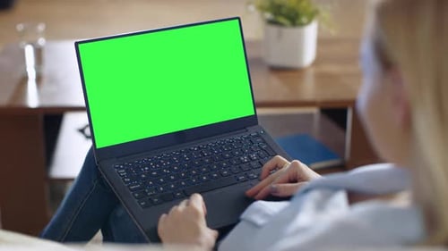 Long Shot of a Smiling Beautiful Woman Sitting on a Couch in Her Living Room. She Works on Her Lapt