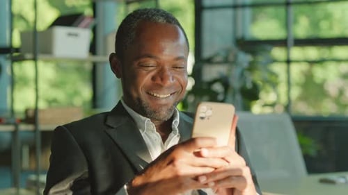 Close Up Face of African American Man Using a Smartphone Texting to Communicate Online Sitting at a