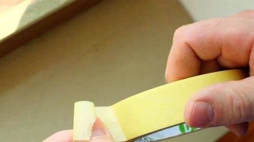 Masking tape. Hands tear off yellow Masking tape.Slow motion.