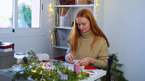 Woman Crafts Christmas Decorations at Home at Table