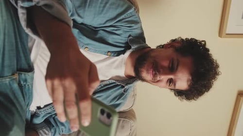 Close-up of smiling man sitting on sofa using mobile phone