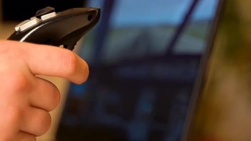 Close up of a person's hand using a precision gaming joystick for flight simulation training.