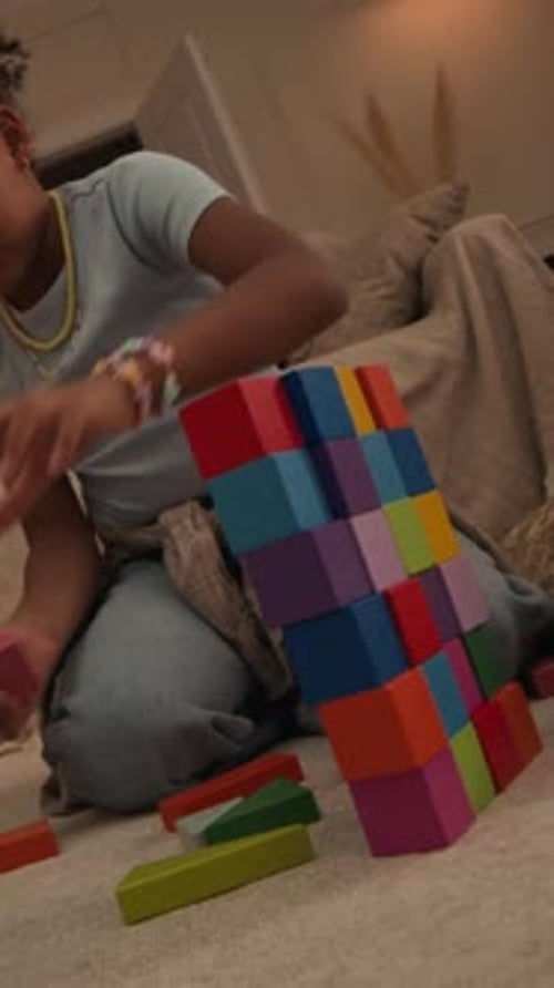 Vertical de una niña birracial que construye una pared de juguete con un papá negro